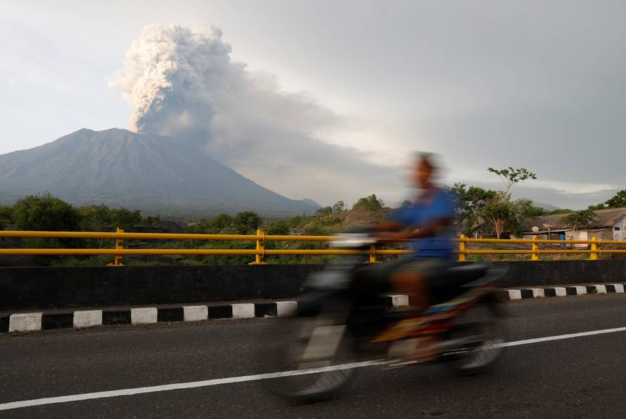 A motorist rides across a bridge as Mount Agung volcano erupts near Kubu in Bali