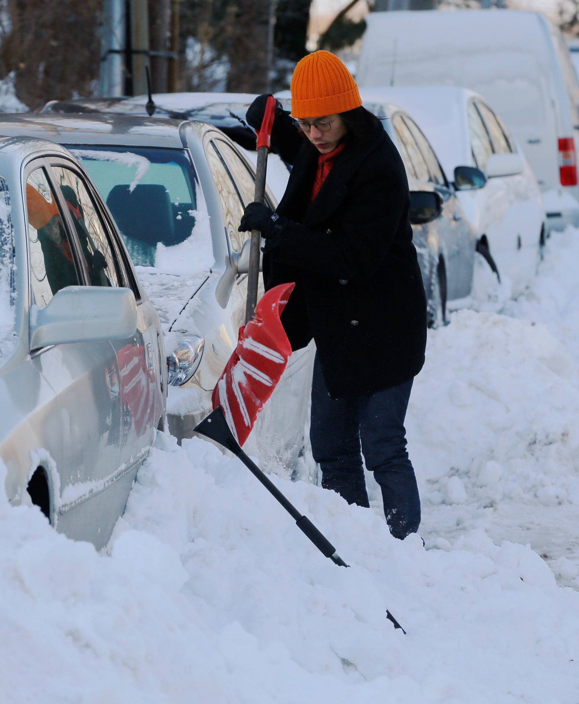 A woman digs out her car following winter snow storm Grayson in Boston