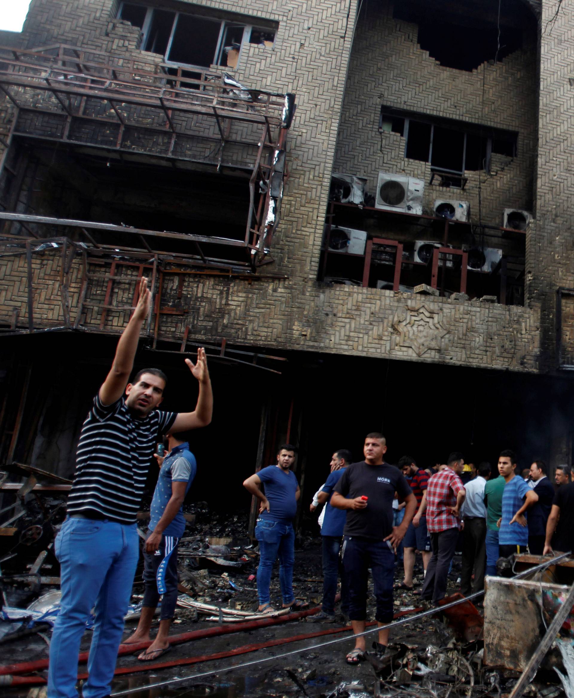 People gather at the site of a suicide car bomb in the Karrada shopping area, in Baghdad, Iraq 