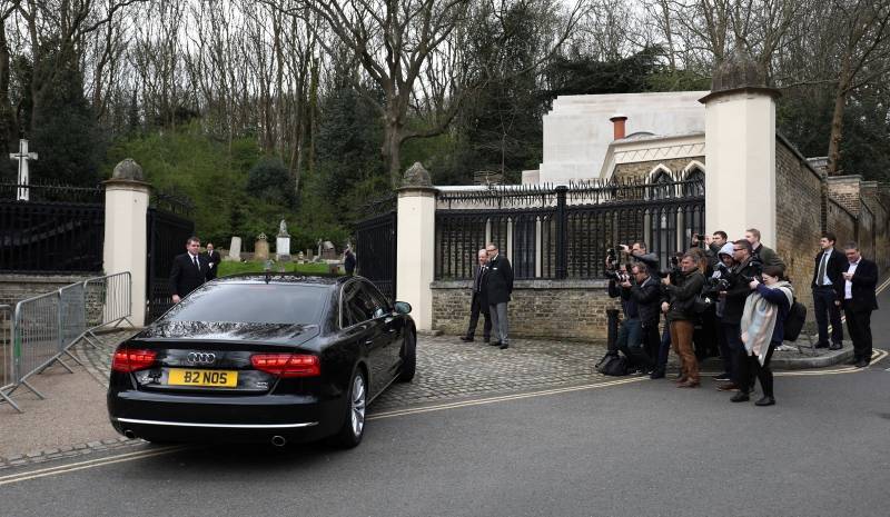 A car drives past members of the media outside Highgate Cemetery in London