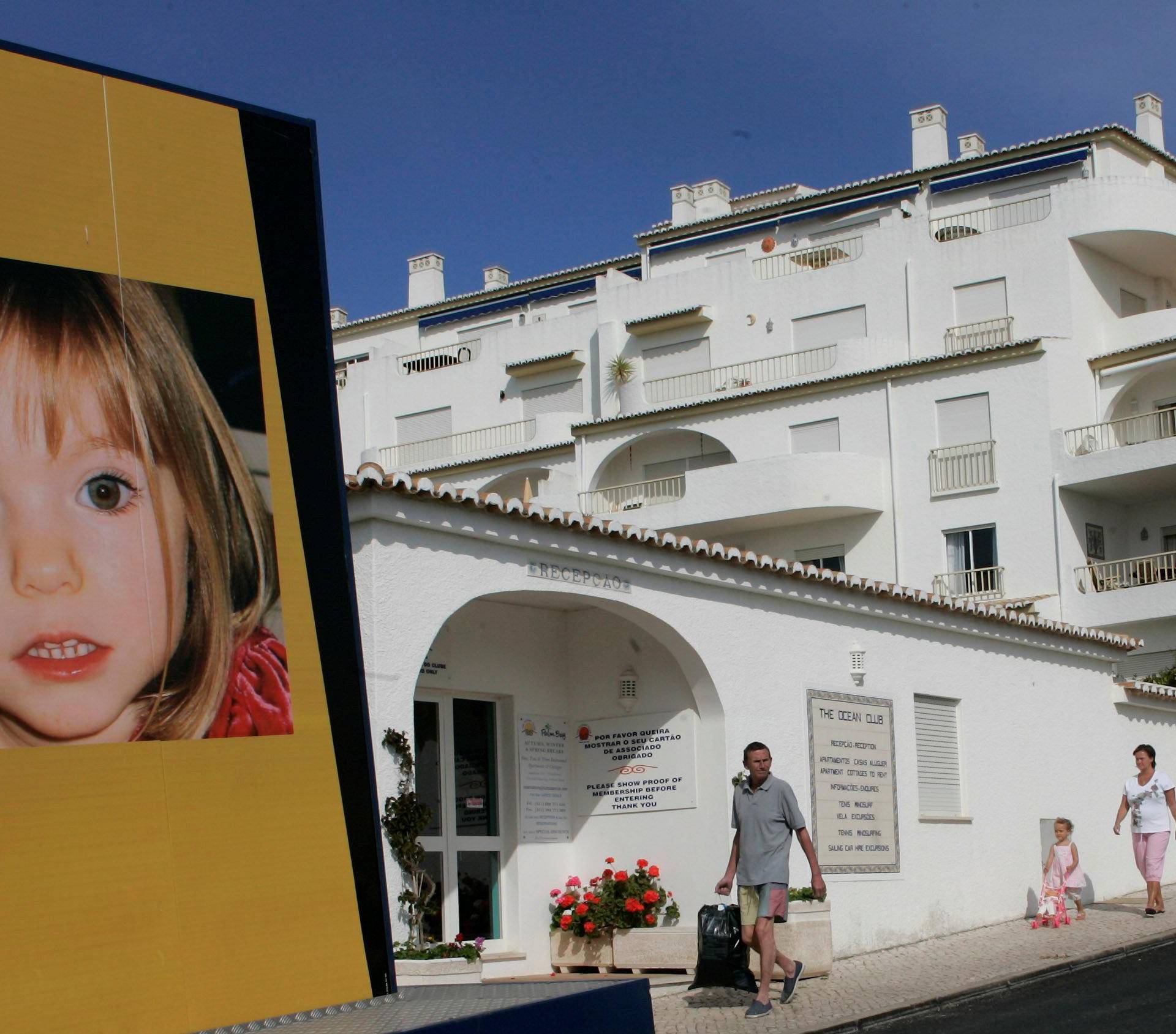 FILE PHOTO - People walk near a billboard at Praia da Luz tourist resort