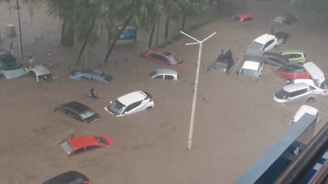 Stranded people sit atop submerged cars amid flooding caused by cyclone Belal, in Port Louis