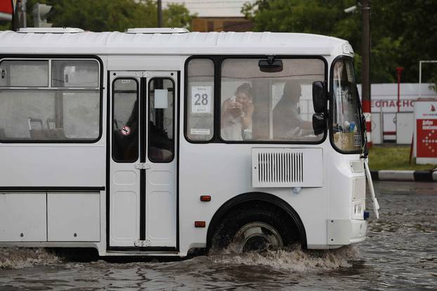 A woman takes a picture as bus drives at the flooded street in Nizhny Novgorod