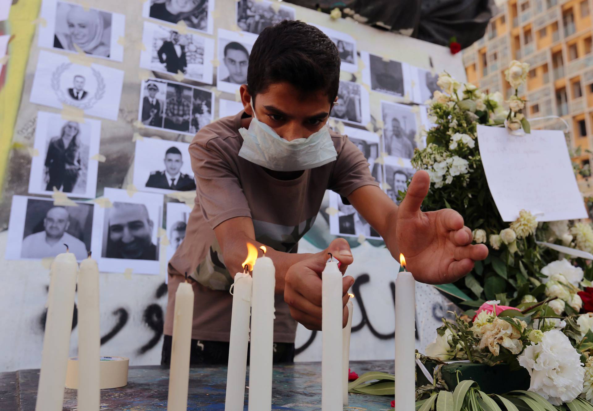 A man lights a candle to mourn the victims of Tuesday's blast in Beirut's port area, at Martyrs' Square in Beirut