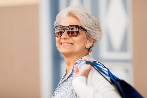 senior woman in sunglasses with shopping bags
