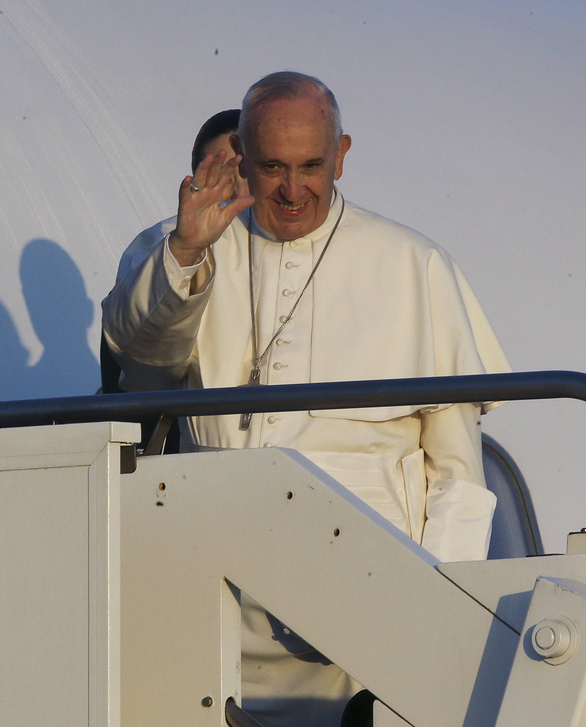 Pope Francis waves as he boards a plane at Fiumicino Airport in Rome