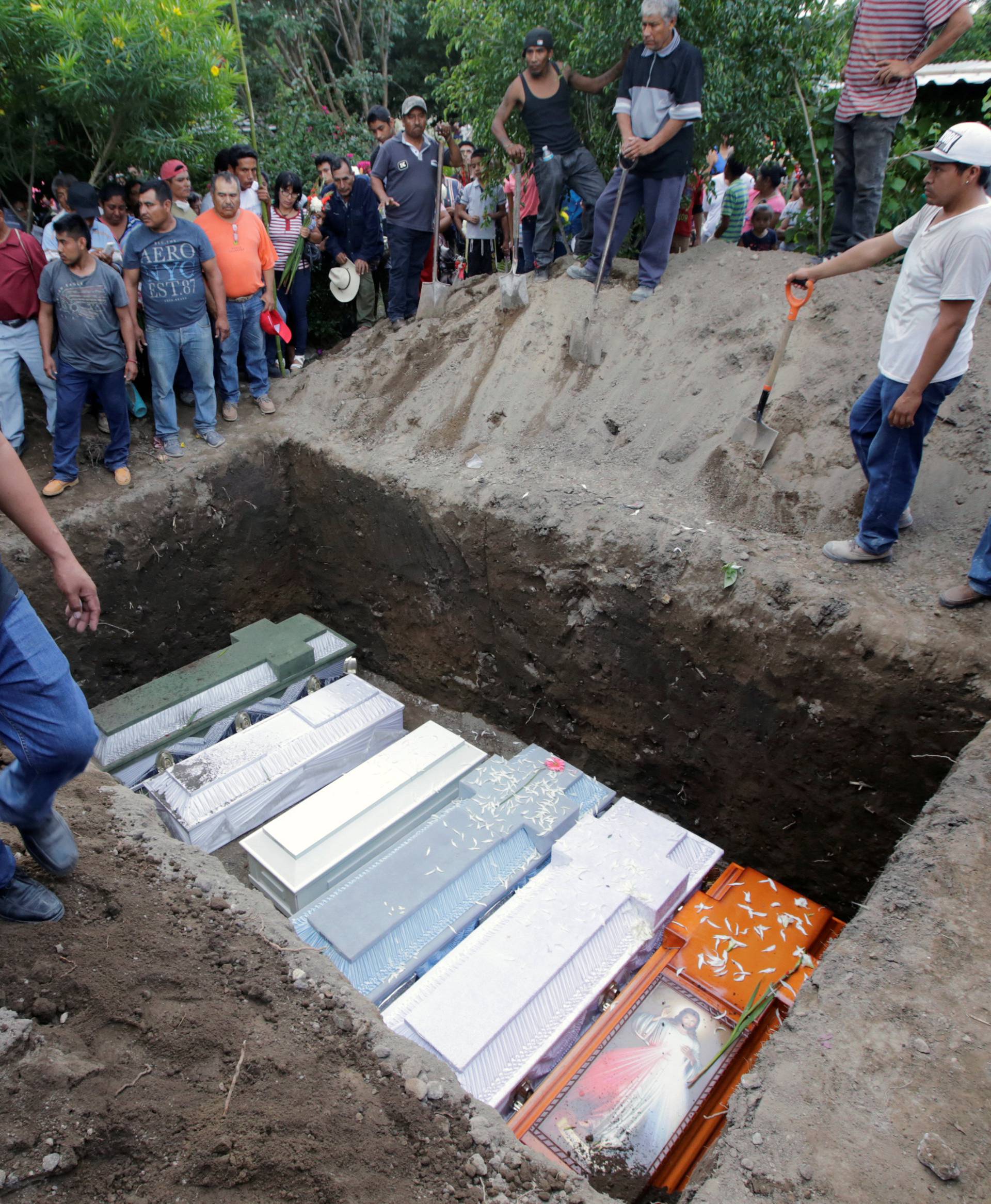 Caskets of earthquake victims are arranged in a grave, in Atzala