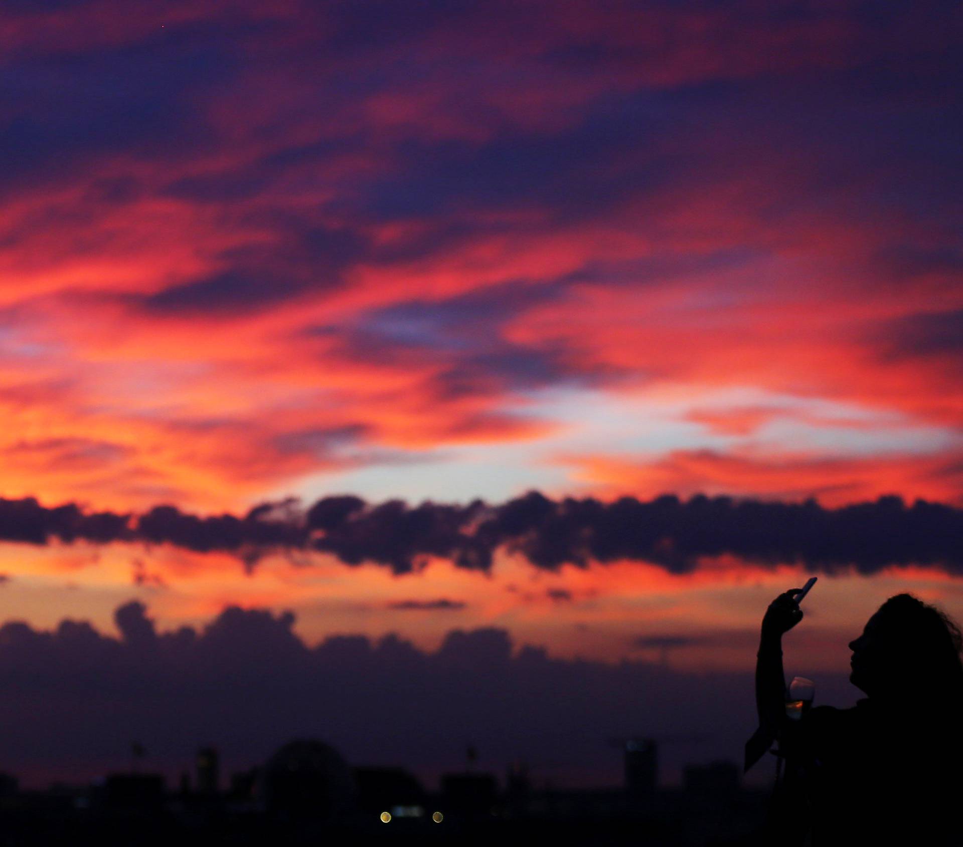 A woman takes pictures of a sunset close to the square Potsdamer Platz in Berlin