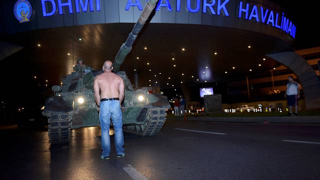 A man stands in front of a Turkish army tank at Ataturk airport in Istanbul