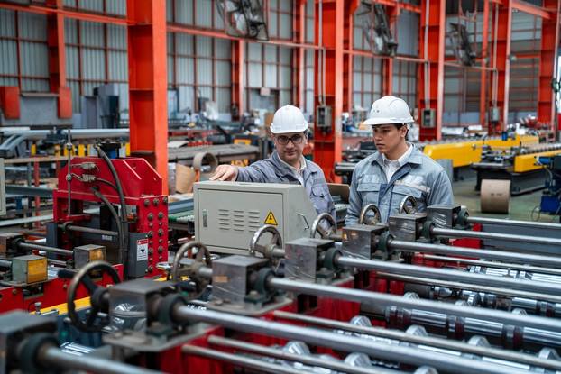Two,Male,Engineers,Stand,And,Talk,About,Machinery,In,A