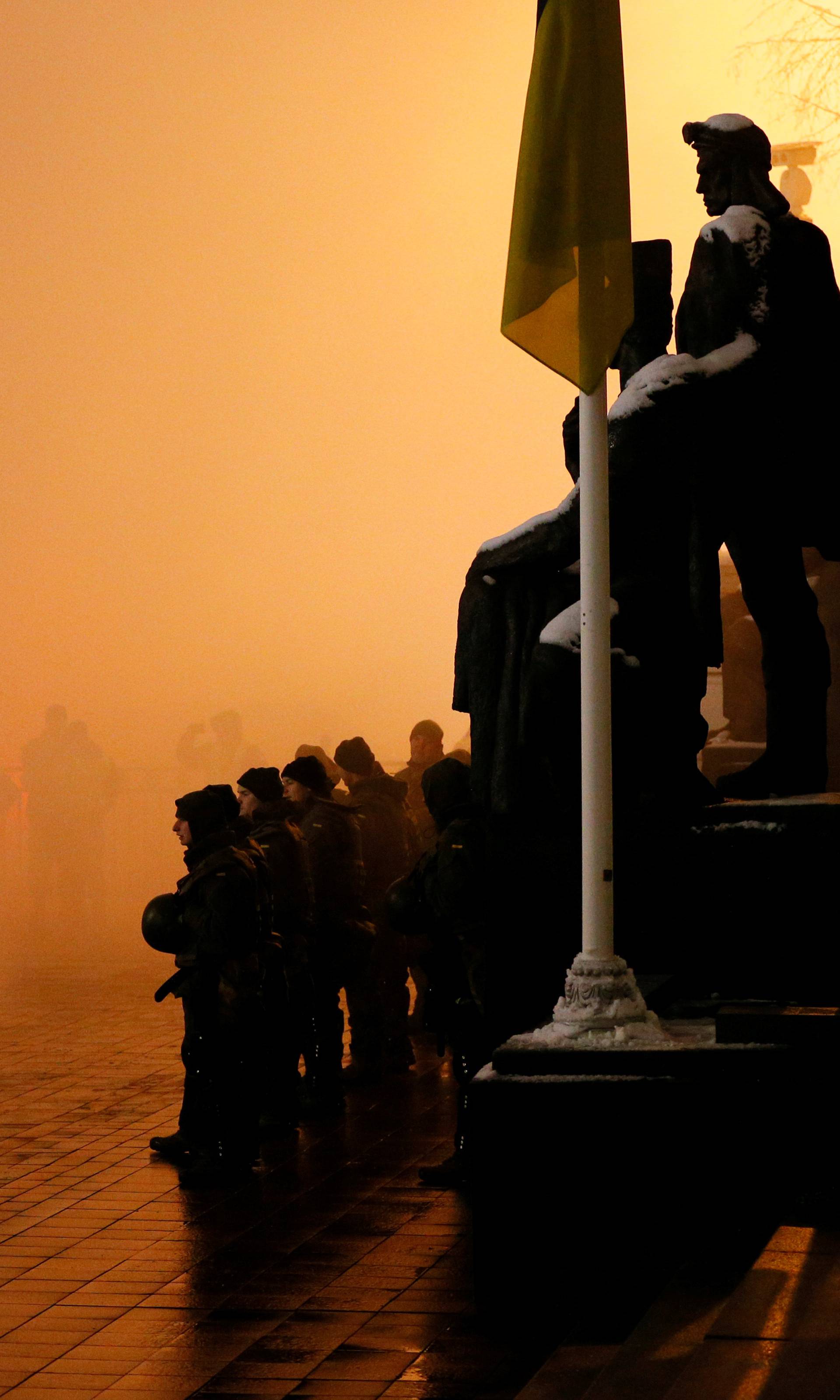 Police officers stand among flare smoke during a rally demanding to break an agreement with Russia on the use of the Azov Sea and the Kerch Strait, in front of the parliament building in Kiev