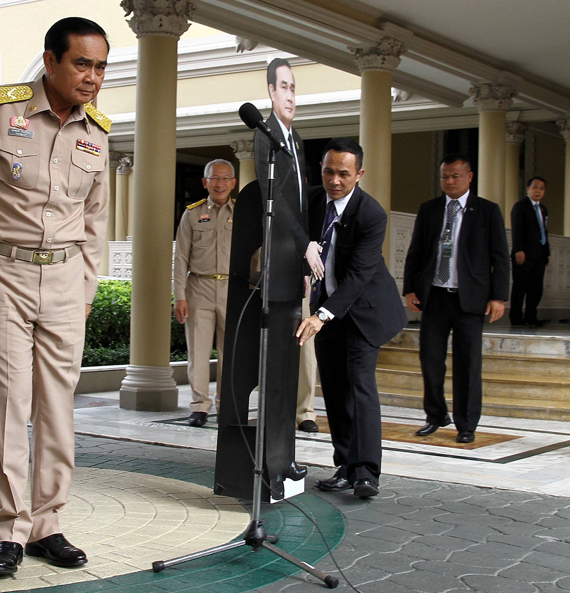 Thailand's Prime Minster Prayuth Chan-ocha speaks to reporters next to a cardboard cut-out of himself at the government house in Bangkok