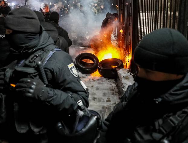 A National Guard serviceman extinguishes a torch thrown by a protester during a rally against the seizure by Russian special forces of three of the Ukrainian navy ships in the Black Sea, in front of the Russian embassy in Kiev