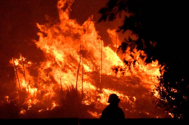 Firefighters battle a wind-driven wildfire called the Saddle Ridge fire in the early morning hours Friday in Porter Ranch