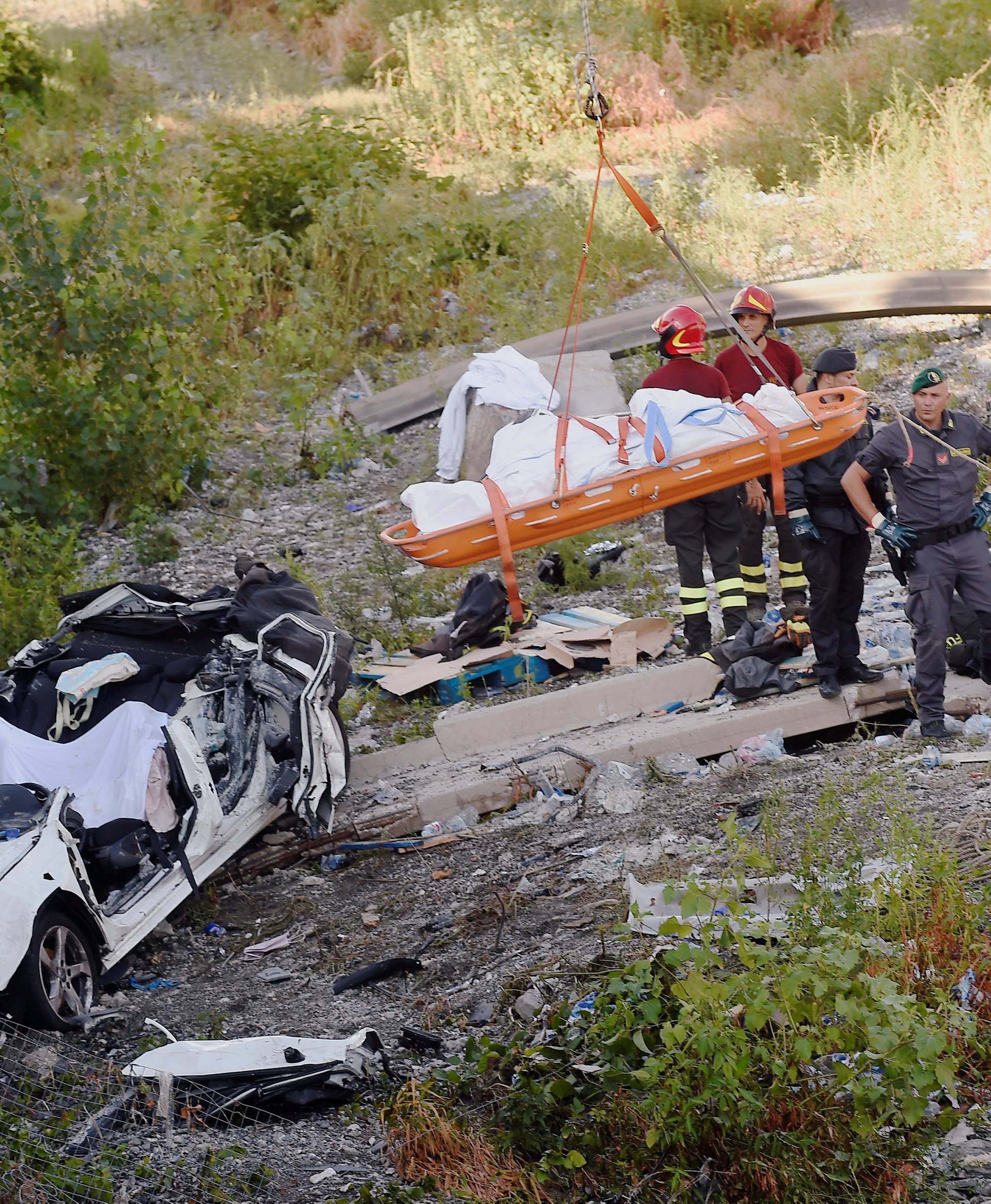 Rescue workers recover a body at the site of the collapsed Morandi Bridge in the port city of Genoa