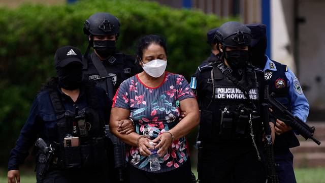 Police officers escort cartel leader Herlinda Bobadilla following an extradition request for her and her sons by the United States, in Tegucigalpa