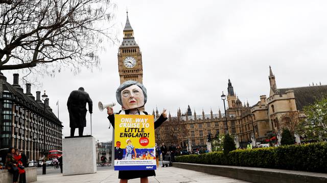 An anti-Brexit protester with a giant Theresa May head wears a sandwich board outside Parliament on the day the Prime Minister will announce that she has triggered the process by which Britain will leave the European Union, in London