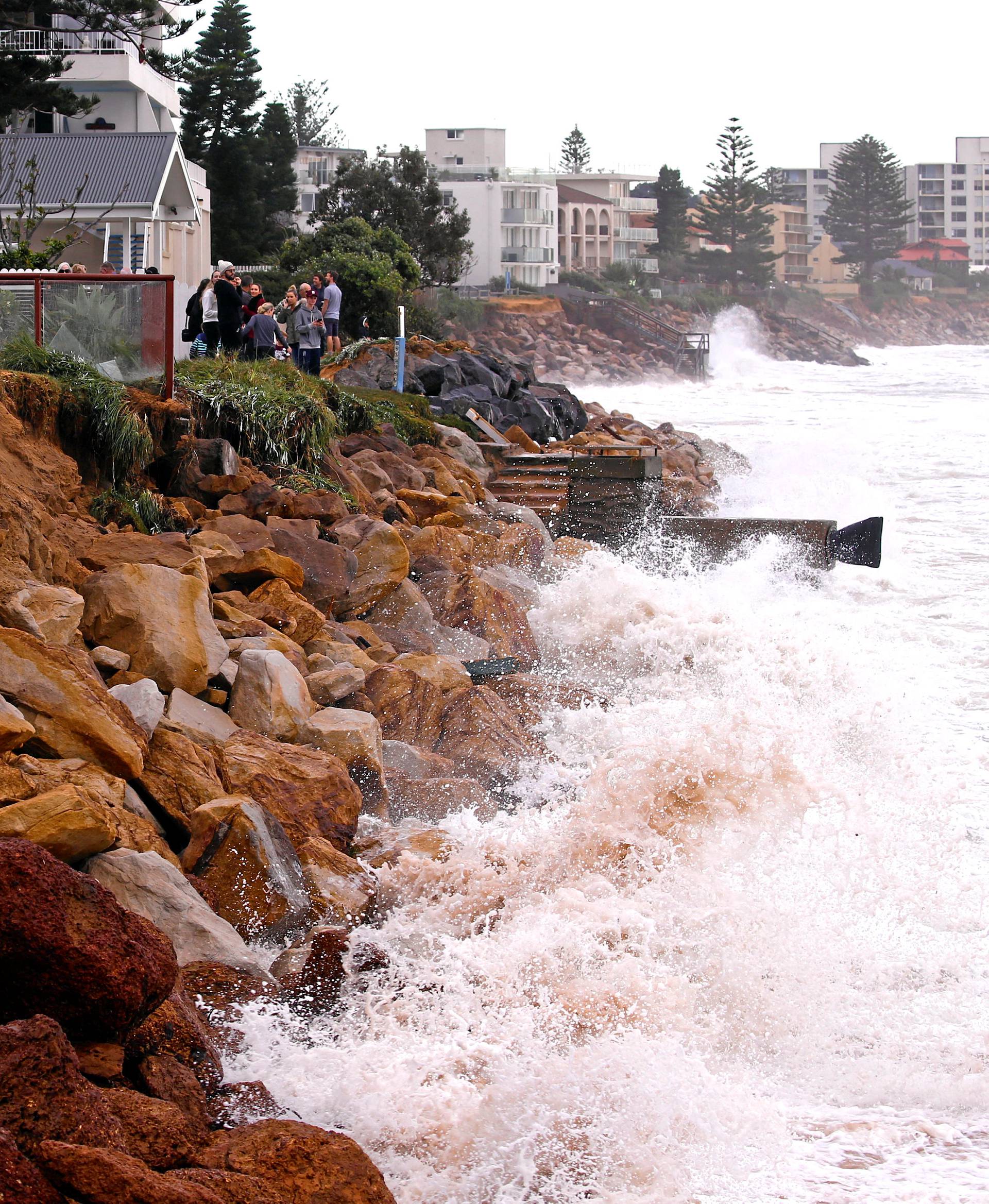 Residents and onlookers inspect the damage to property and a rock wall after severe weather brought strong winds and heavy rain to the east coast of Australia at Collaroy beach in Sydney, Australia