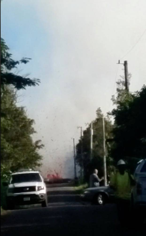 Lava spurts from the ground as emergency vehicles block a road near Kilauea Volcano after it erupted, on Hawaii