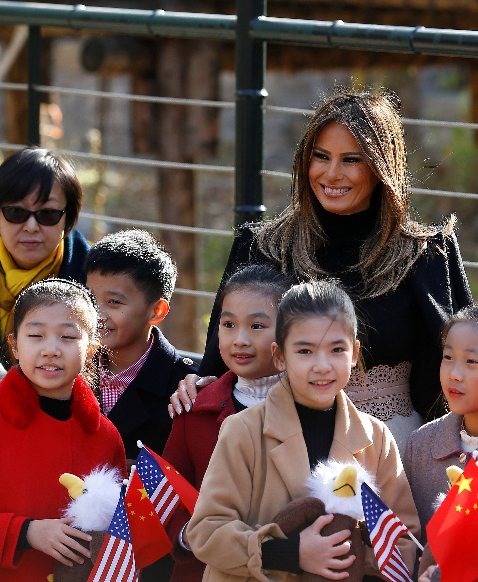 U.S. first lady Melania Trump smiles with children holding U.S. and China flags as she visits Beijing Zoo in Beijing,