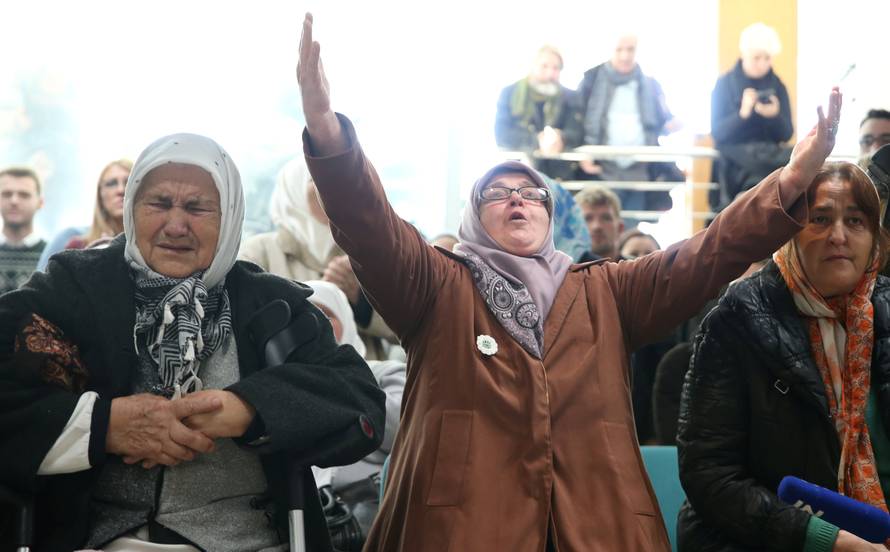 A woman reacts as she watches a television broadcast of the court proceedings of former Bosnian Serb general Ratko Mladic in the Memorial centre Potocari near Srebrenica
