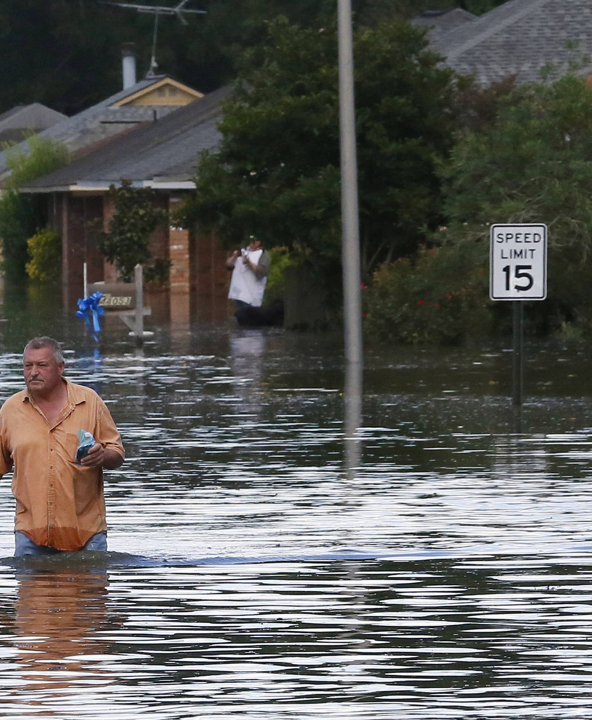 A man wades through a flooded street in Ascension Parish