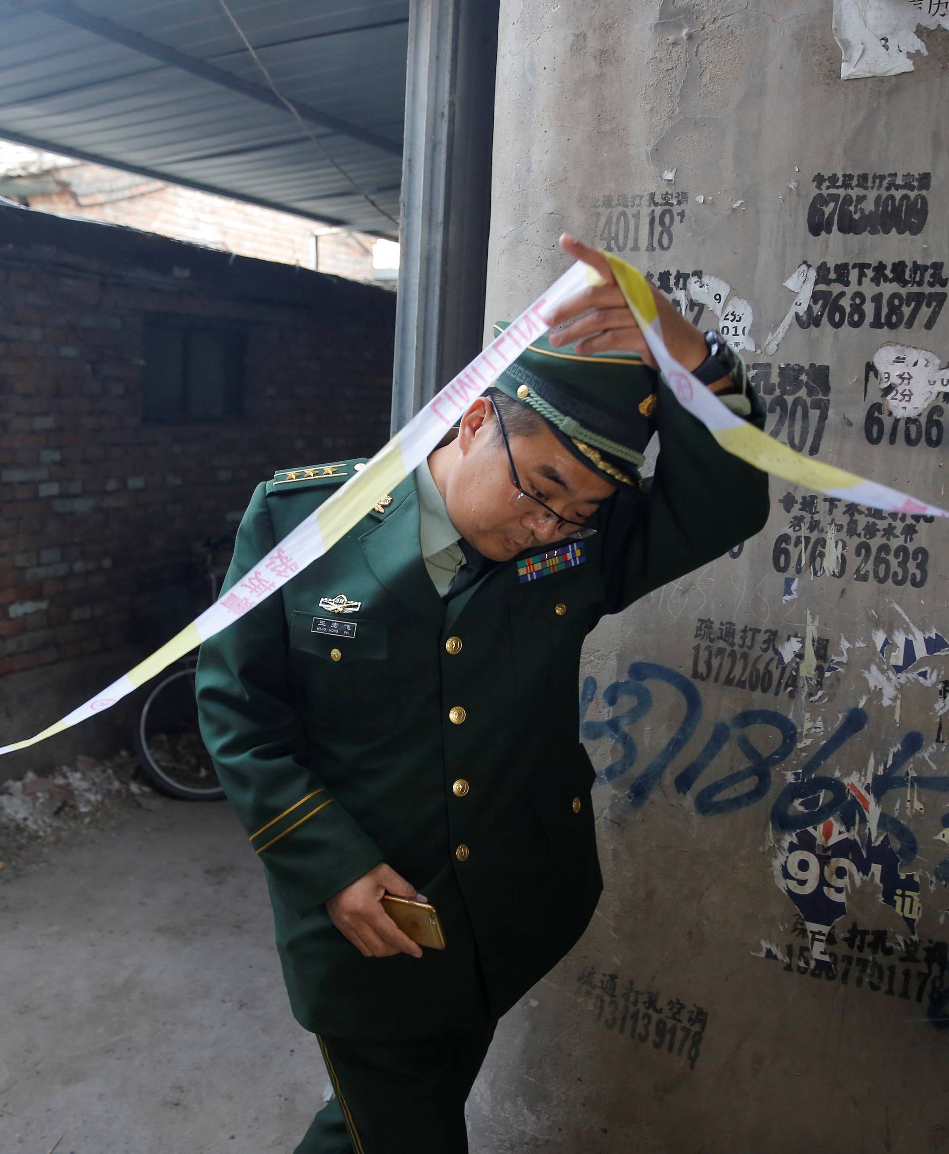 An investigator enters a house where a fire killed several people in Baiqiangzi village in Beijing