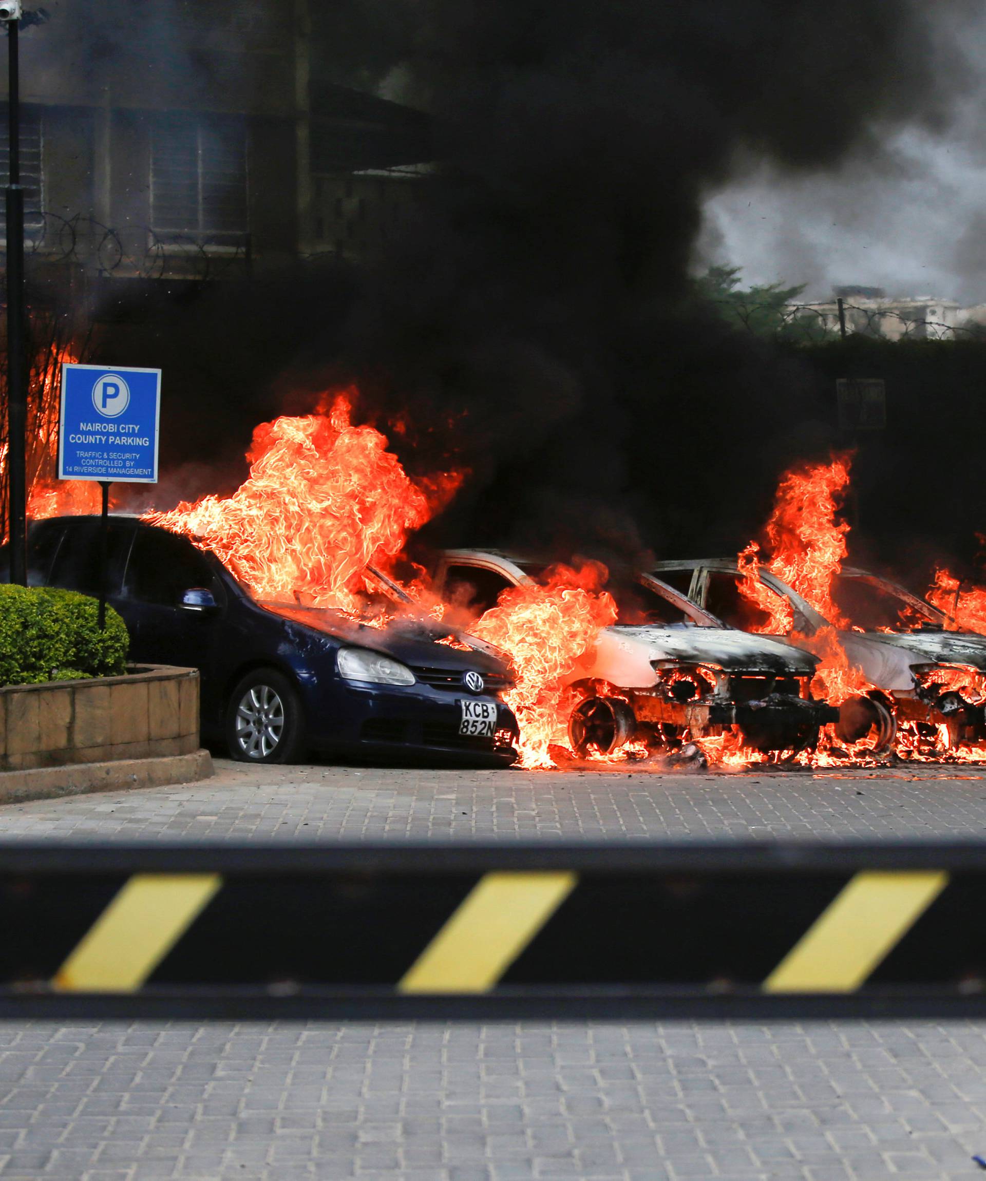 Burning cars are seen at the scene where explosions and gunshots were heard at the Dusit hotel compound, in Nairobi