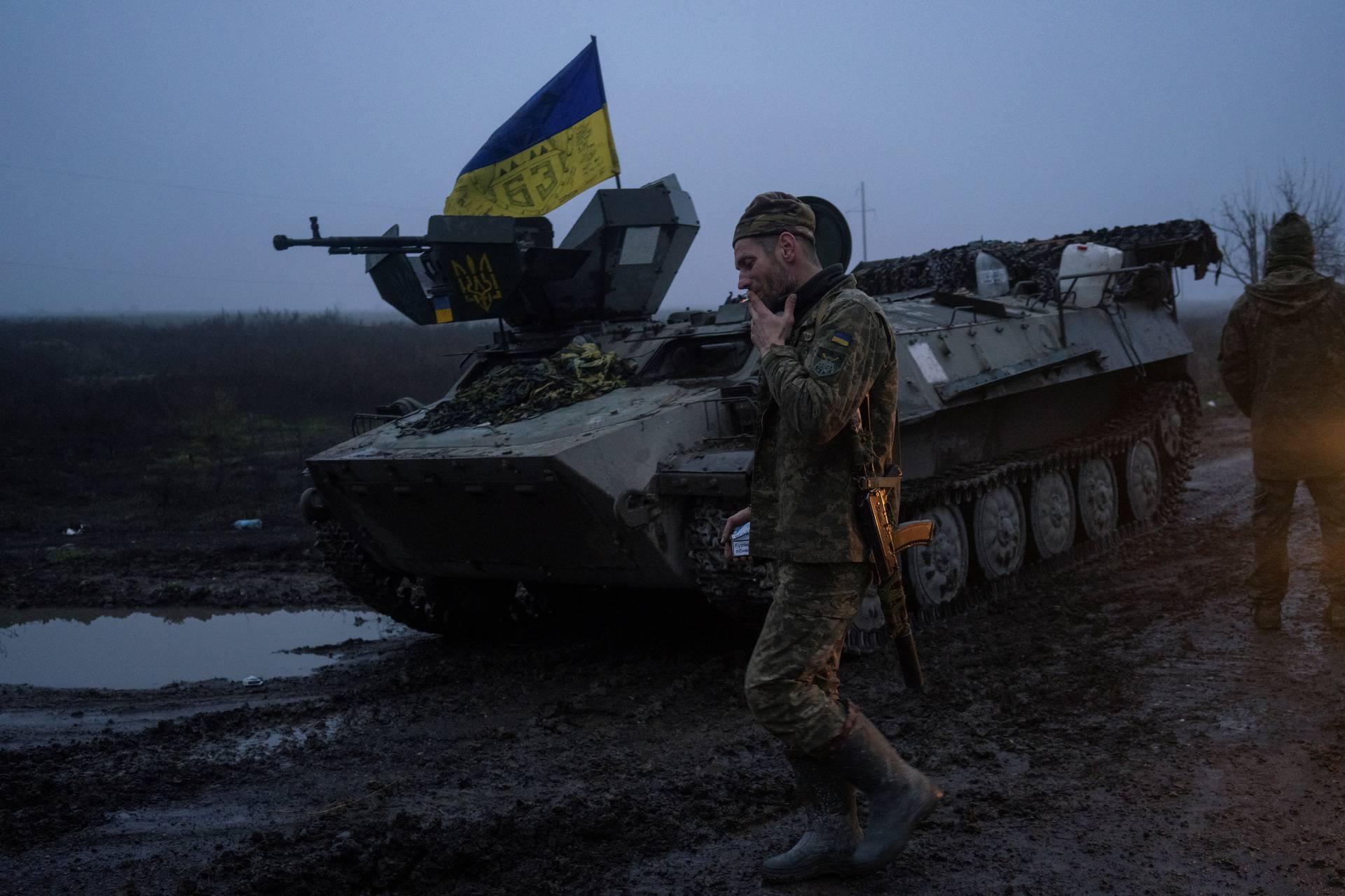 Ukrainian service member smokes next to an armoured personnel carrier on a road in Kherson region