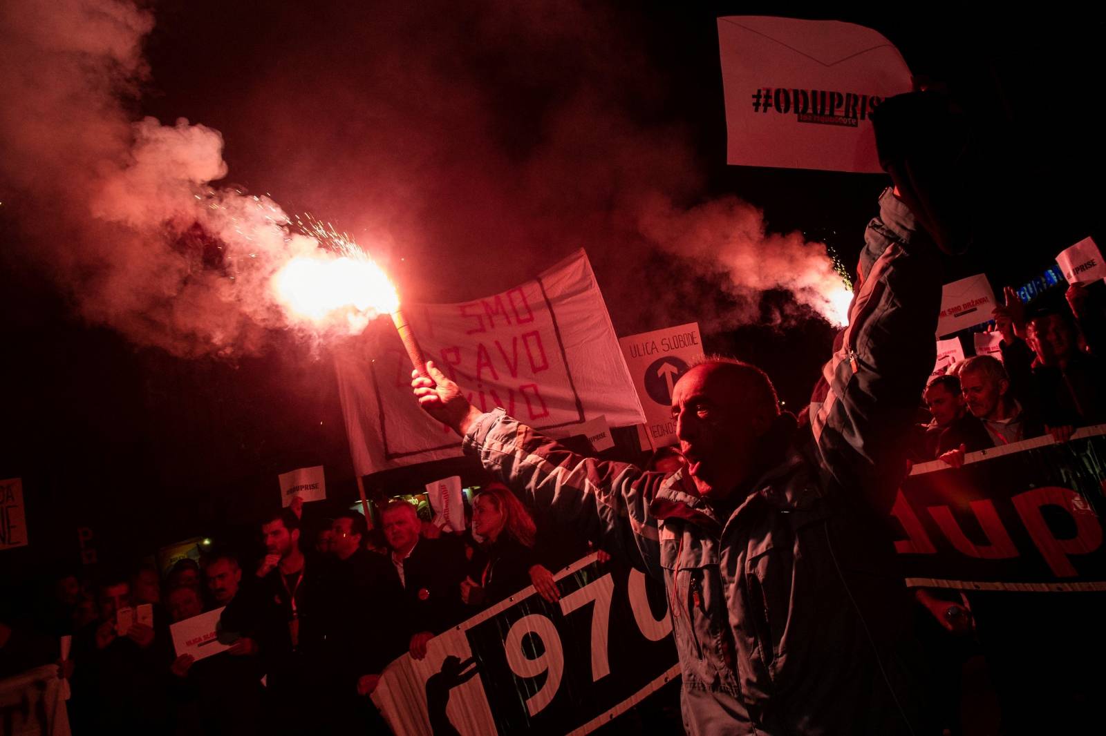 A demonstrator holds a flare during civic protest in Podgorica