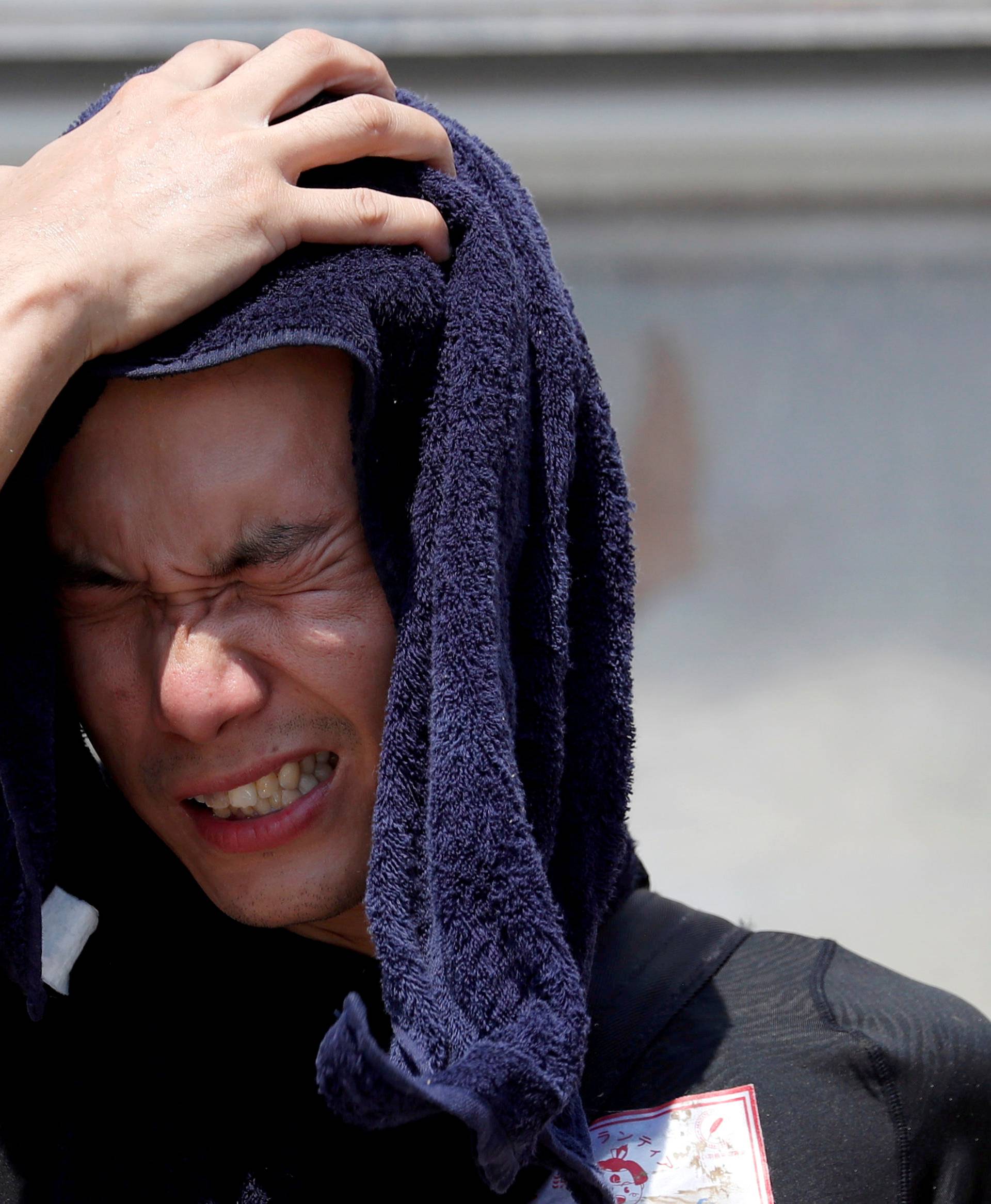 FILE PHOTO: A volunteer, for recovery work, wipes his sweat as he takes a break in a heat wave at a flood affected area in Kurashiki