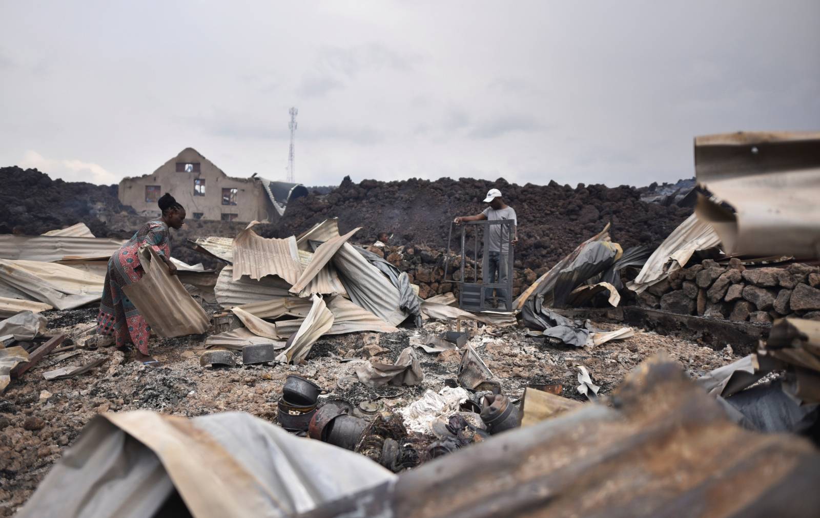 Residents pick up remains of their destroyed homes from the smouldering lava deposited by the eruption of Mount Nyiragongo volcano near Goma