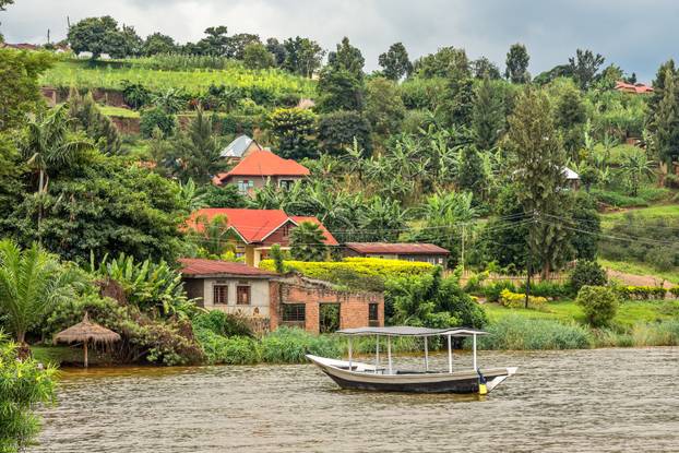 Roof boat anchored at the coast with rwandan village in the back