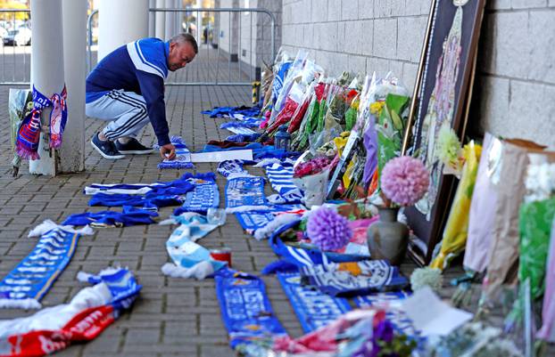 A Leicester City football fan places a scarf outside the football stadium, after the helicopter of the club owner Thai businessman Vichai Srivaddhanaprabha crashed when leaving the ground on Saturday evening after the match, in Leicester