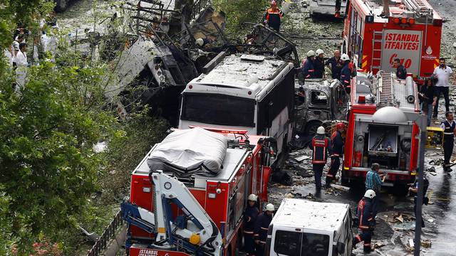 Forensic experts and firefighters stand beside a Turkish police bus which was targeted in a bomb attack in Istanbul