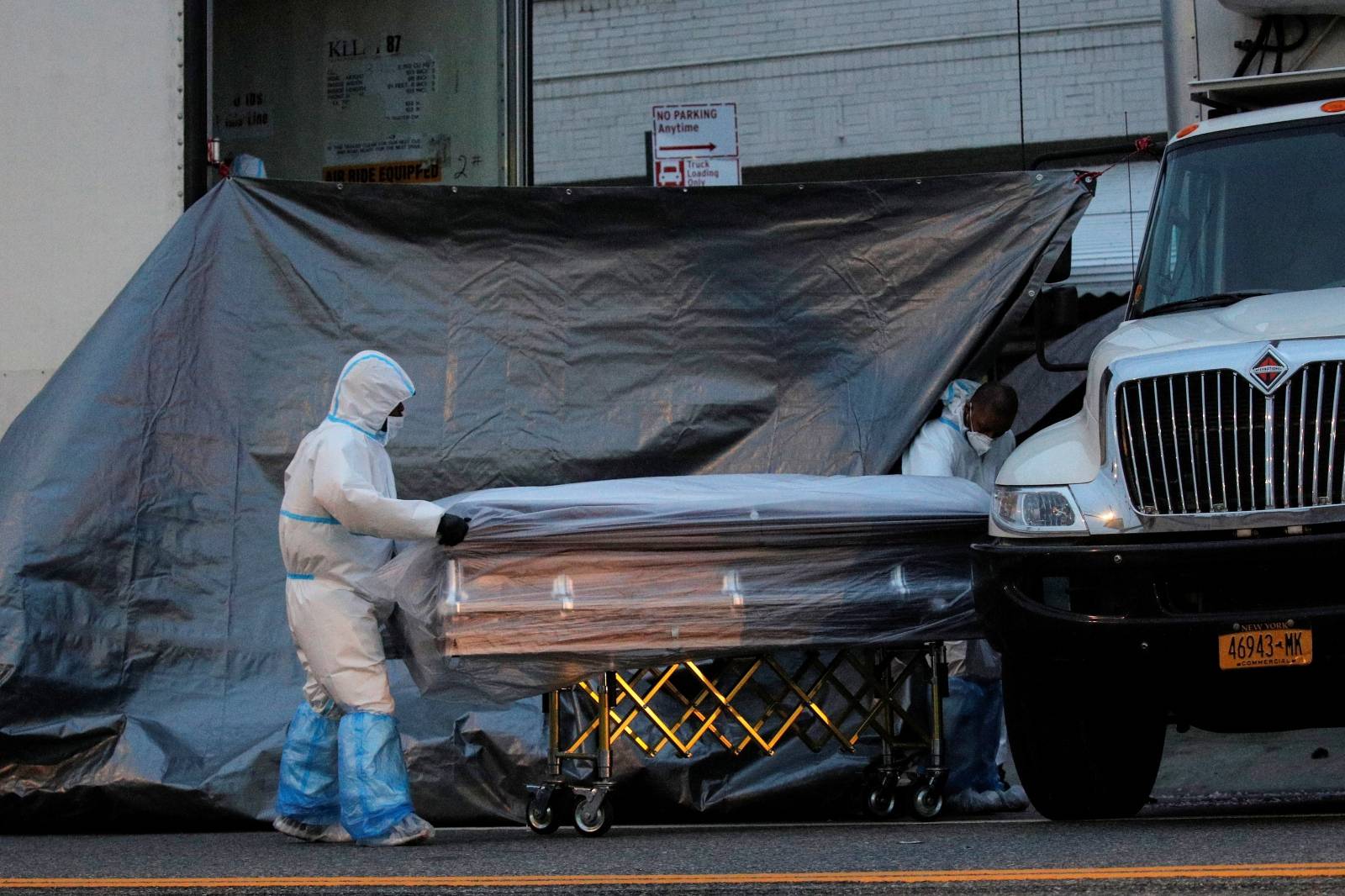 Workers roll a casket down a city street outside the Andrew T. Cleckley Funeral Services funeral home during the outbreak of the coronavirus disease (COVID-19) in Brooklyn, New York