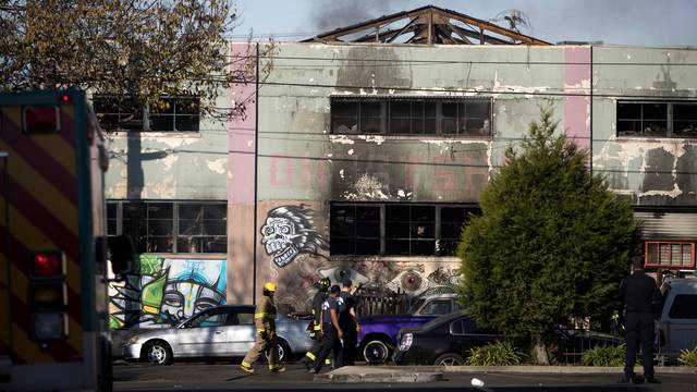 Firefighters stand outside a warehouse after a fire broke out during an electronic dance party late Friday evening, resulting in at least nine deaths and many unaccounted for in the Fruitvale district of Oakland, California