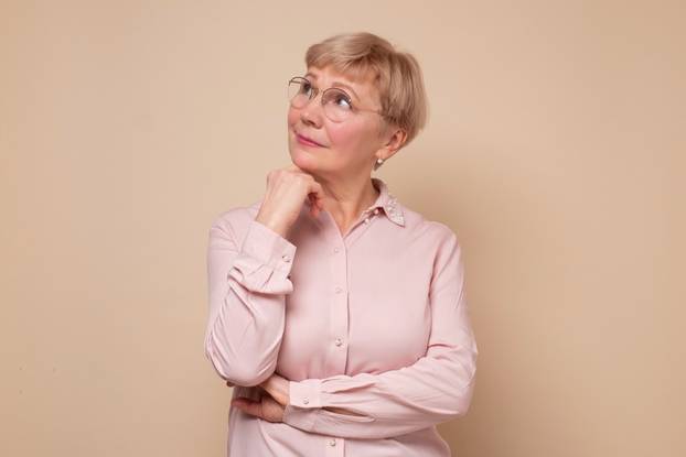 Thinking senior woman in glasses thinking trying to make a decision.