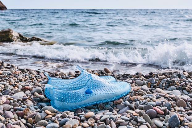 Rubber blue women's slippers for swimming on a pebble beach