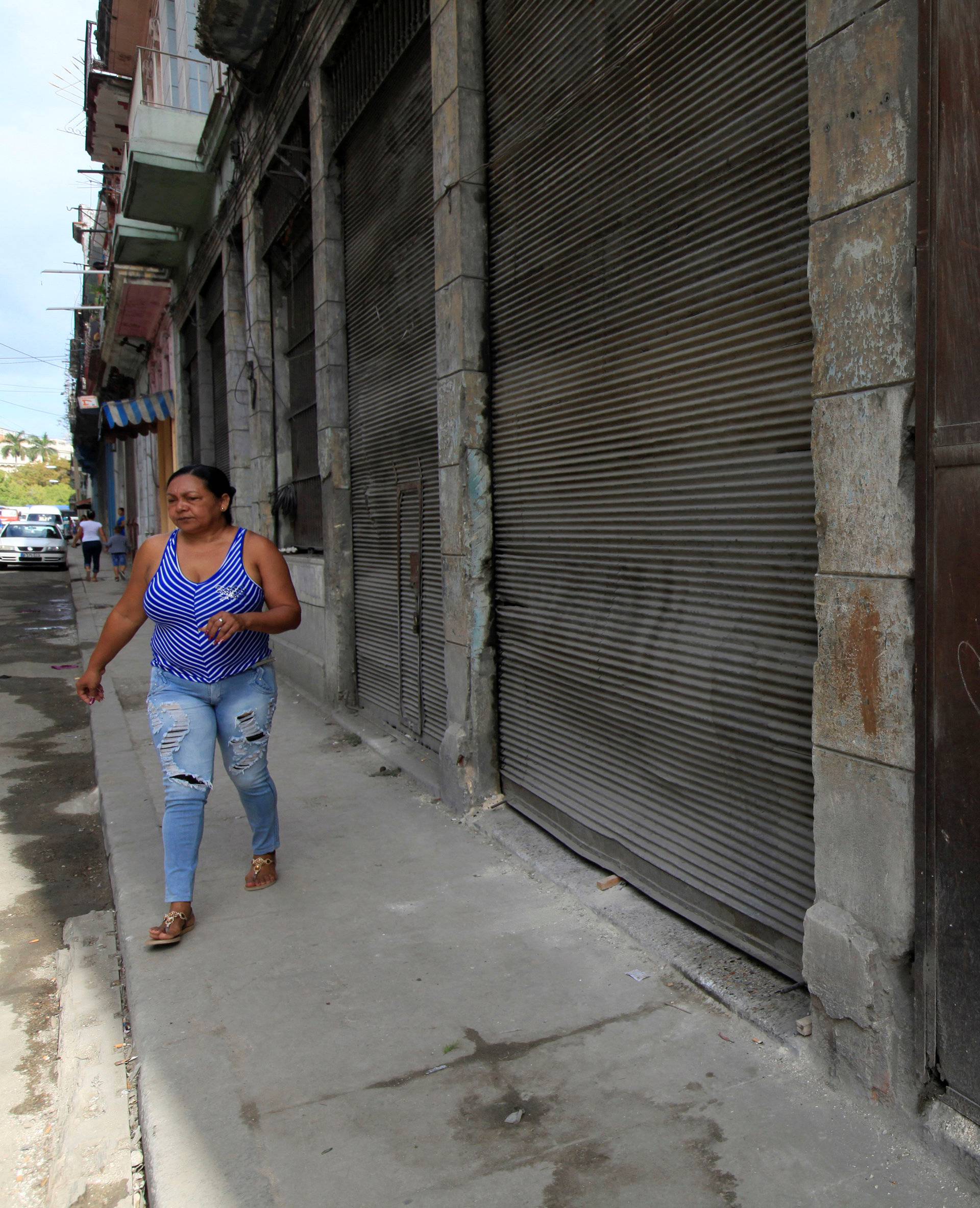 A woman walks past a graffiti that reads "Long live Fidel and Raul" in Havana, Cuba