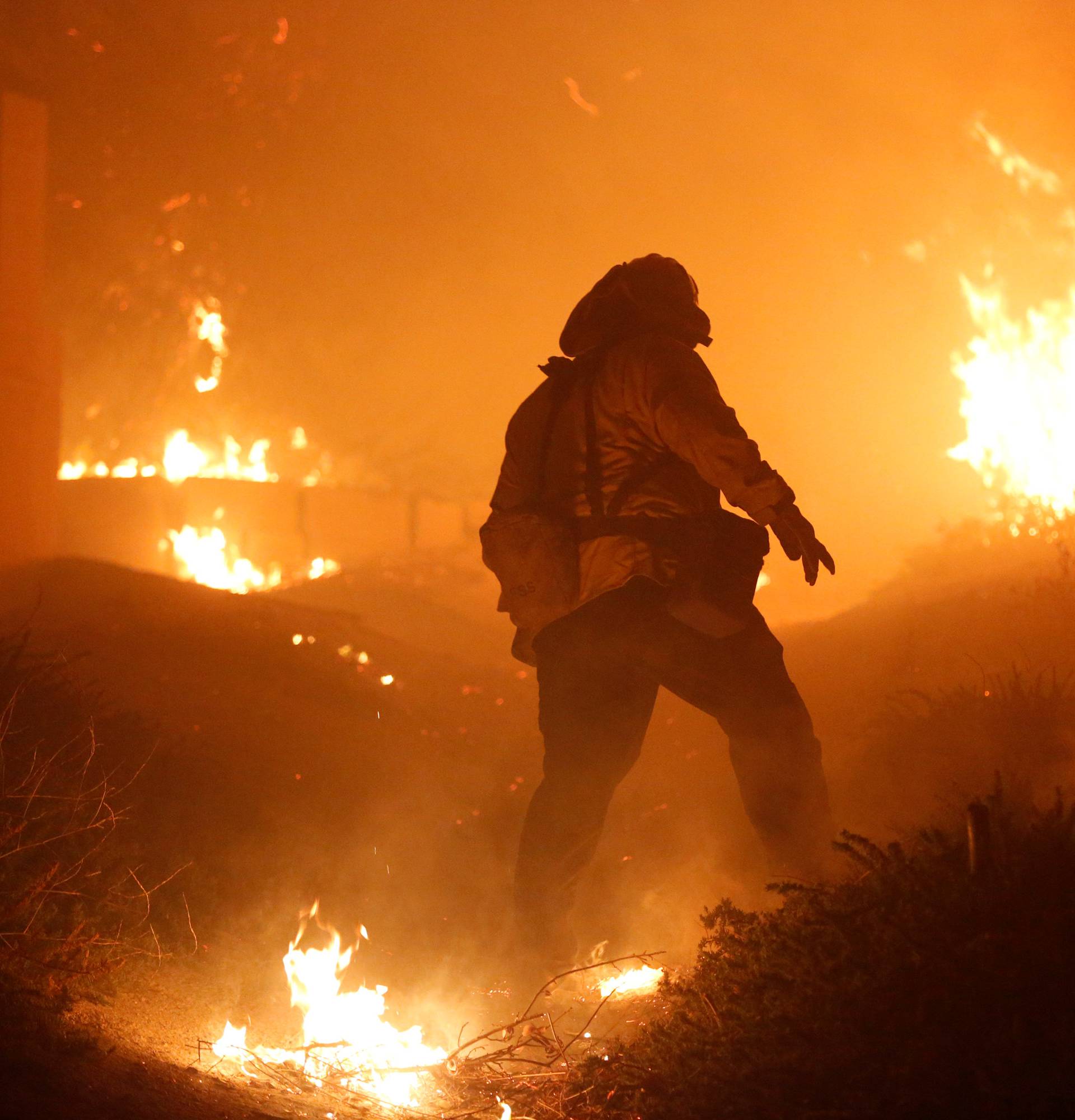 A firefighter stomps out small embers near a home threatened by the Creek Fire in Sylmar, California