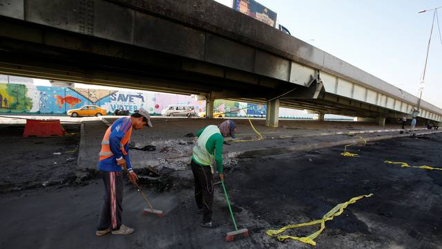 Municipal workers sweeps the ground at the site of a suicide bomb attack at Nakheel Mall across from the oil ministry, in Baghdad