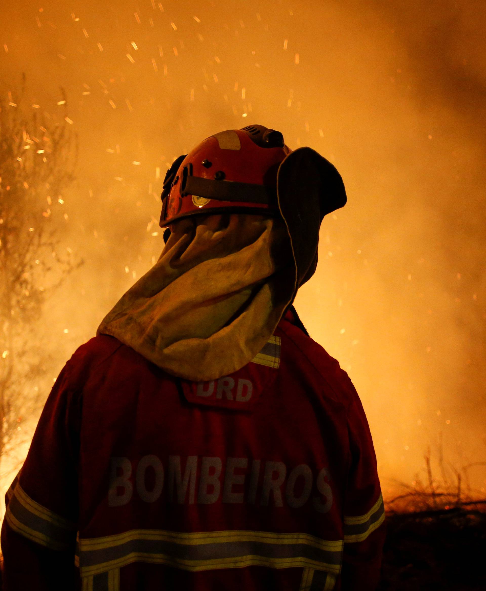 A firefighter is seen near flames from a forest fire in Cabanoes near Lousa