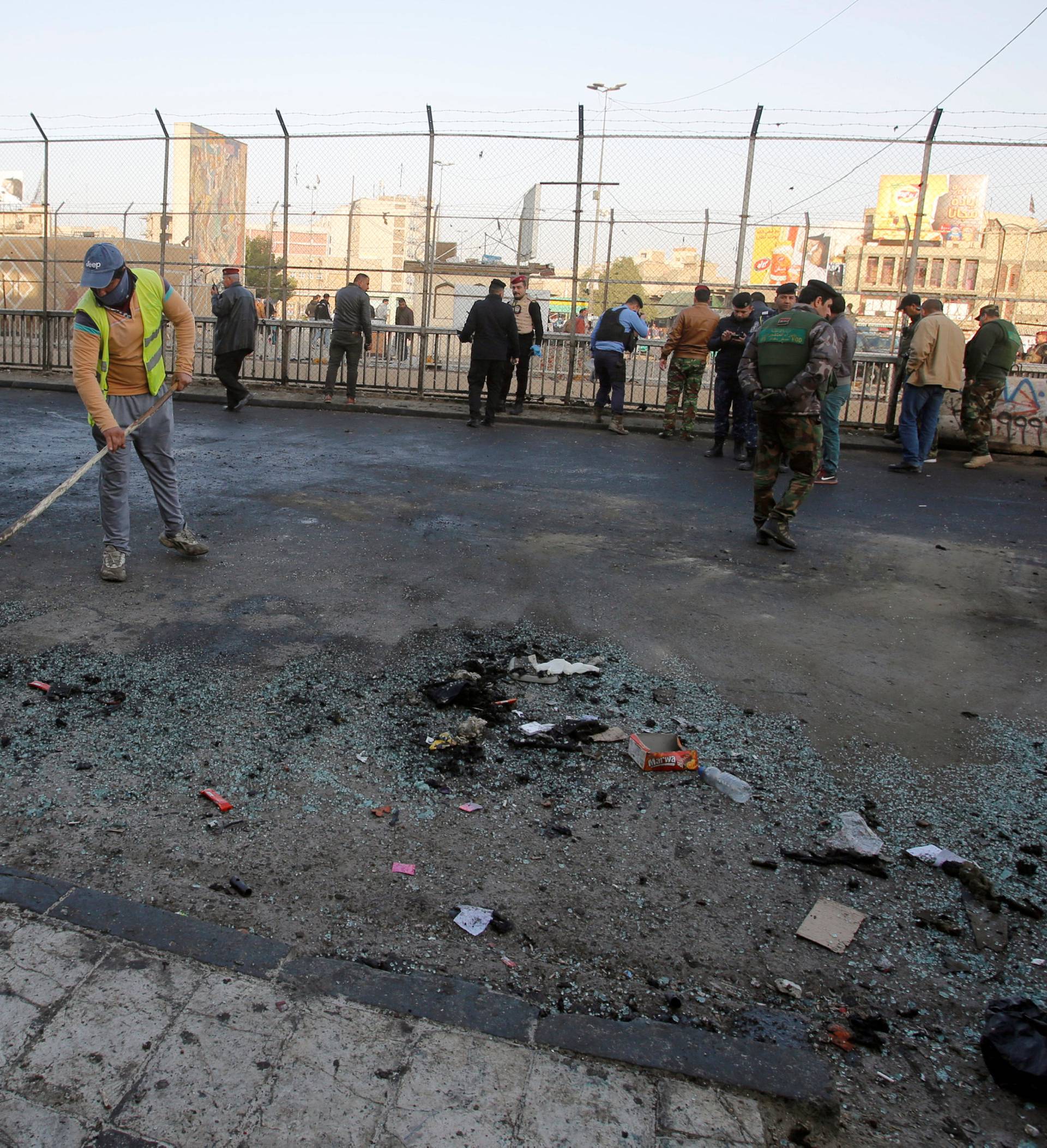 Iraqi security forces inspect the site of a bomb attack in Baghdad