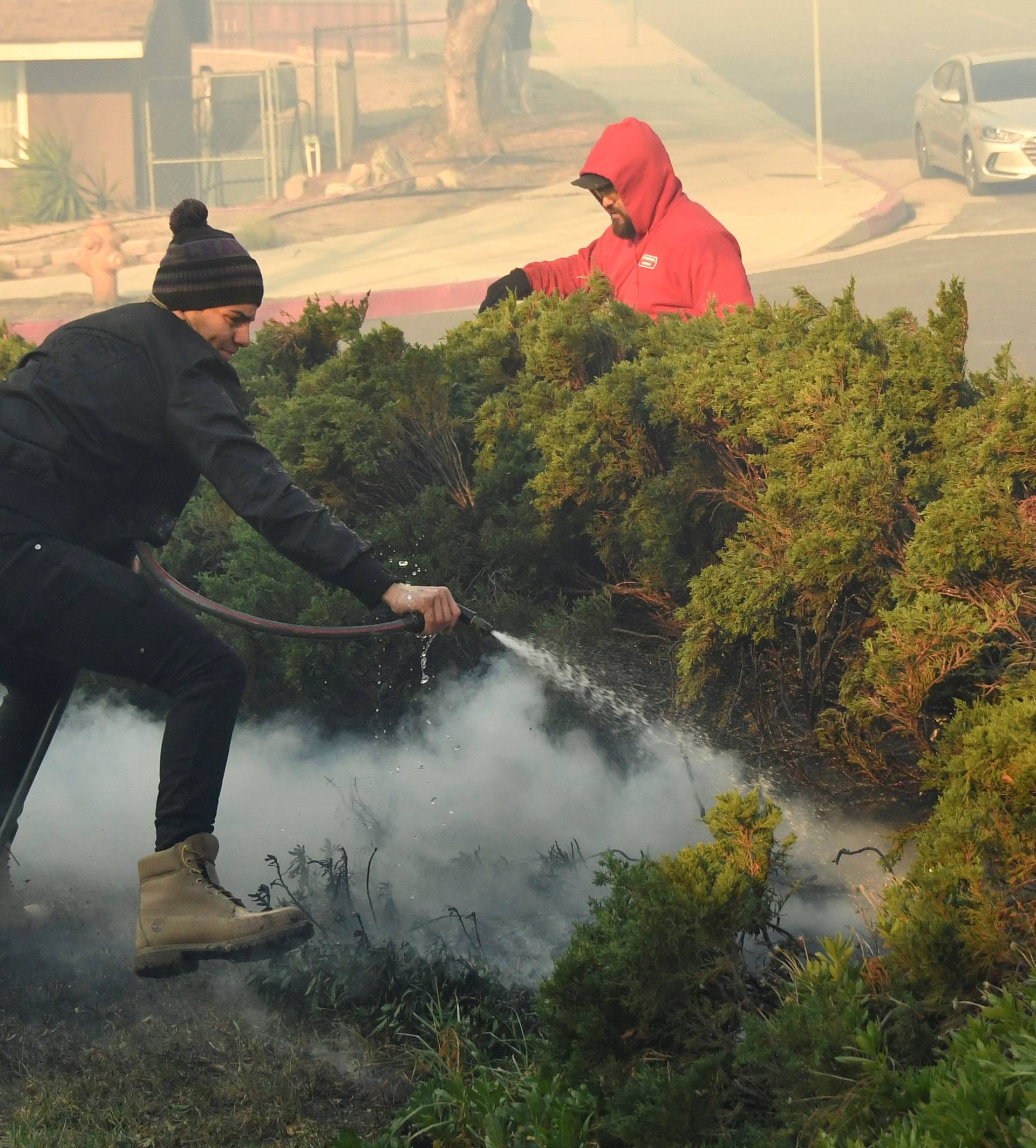 Local neighbors put out hot spots from the heavy winds that started a early-morning Creek Fire that broke out in the Kagel Canyon area in the San Fernando Valley north of Los Angeles