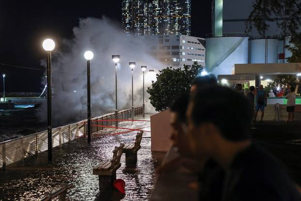 Residents watch rough waves from the shore before Super Typhoon Ragasa makes its closest approach to Hong Kong, in Hong Kong