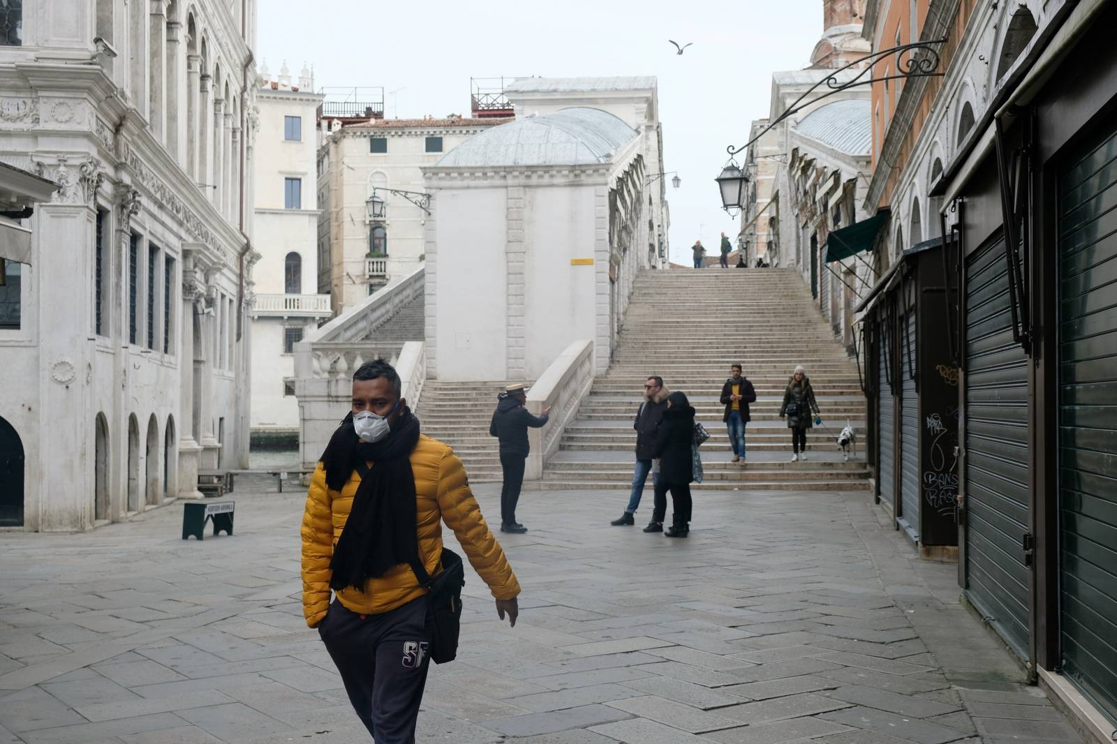 A man wearing a protective face mask walks through a street after the Italian government imposed a virtual lockdown on the north of Italy including Venice to try to contain a coronavirus outbreak, in Venice