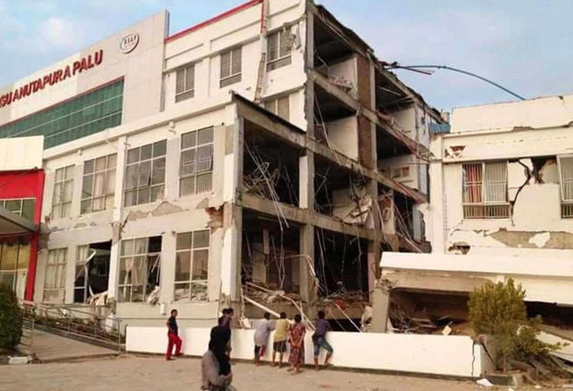 People stand outside of damage hospital after an earthquake hit in Palu