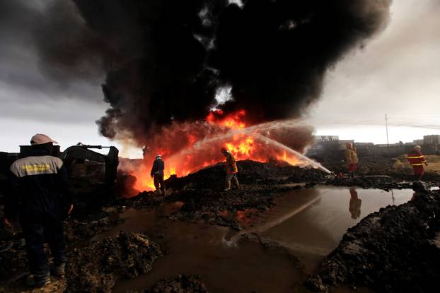 Firefighters work to extinguish the fire at oil wells set ablaze by Islamic State militants before they fled the oil-producing region of Qayyara