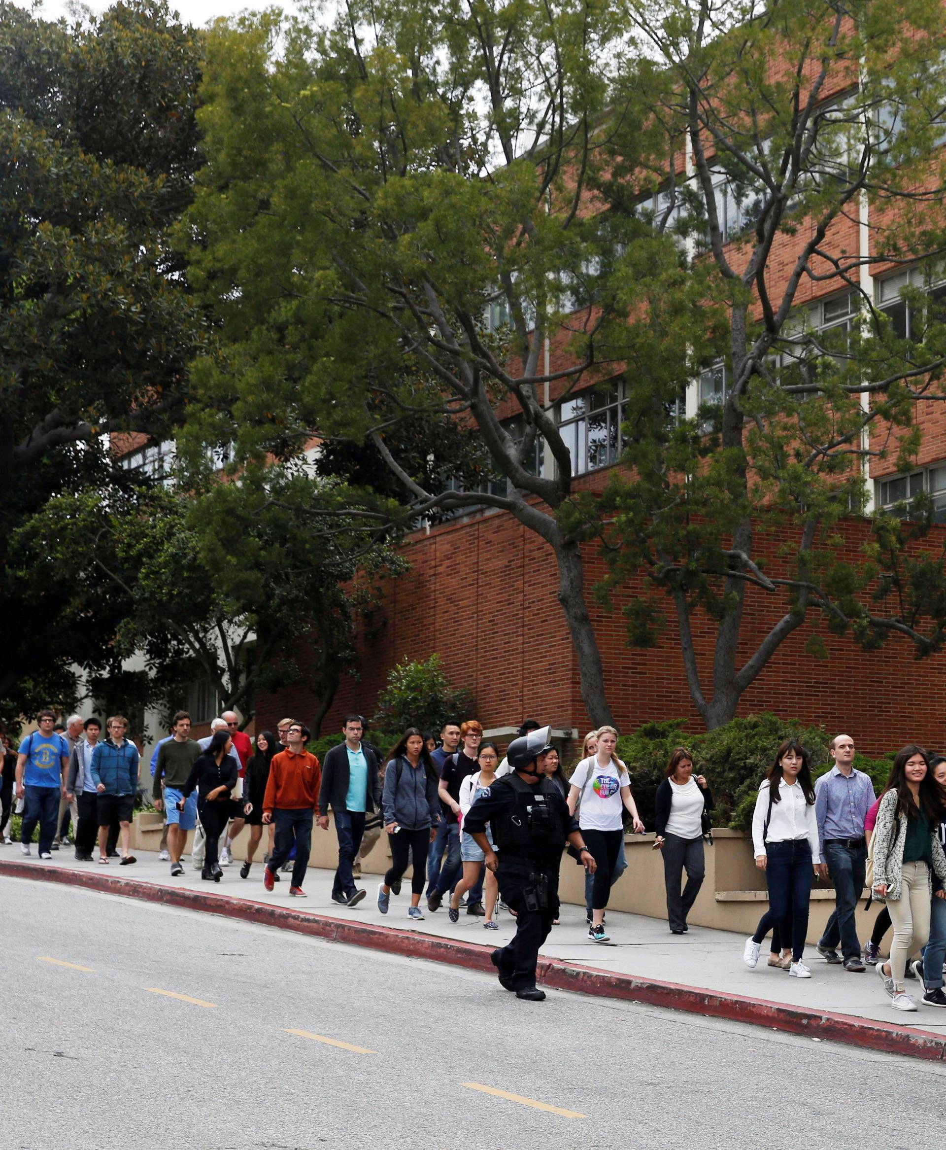 Police officers escort people after a search at the University of California, Los Angeles (UCLA) campus after it was placed on lockdown following reports of a shooter that left 2 people dead in Los Angeles